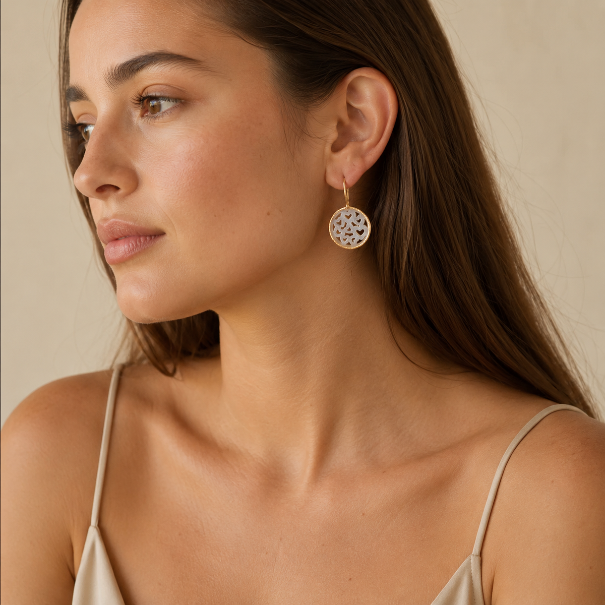 Gold-plated drop earrings with mother of pearl heart cutouts.