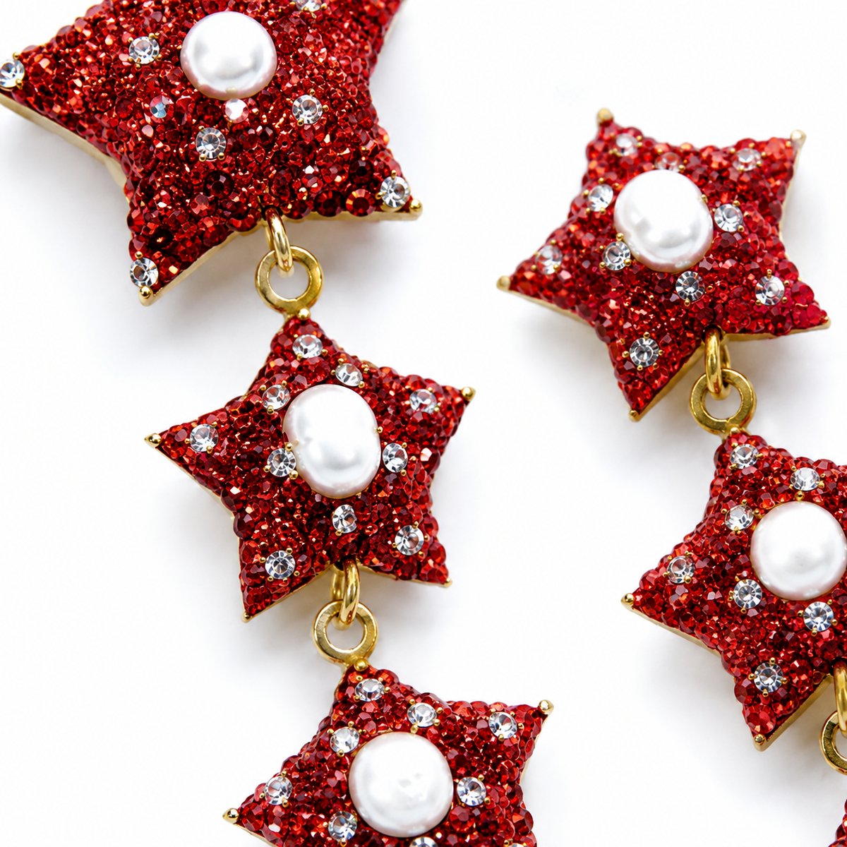 Close view of red star earrings with sparkling CZ details and gold-tone links.