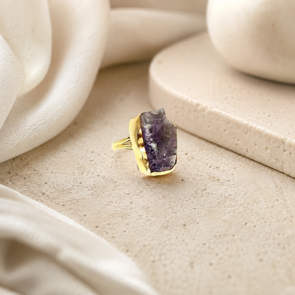 Gold-plated ring with a raw amethyst stone in a sculptural shape.