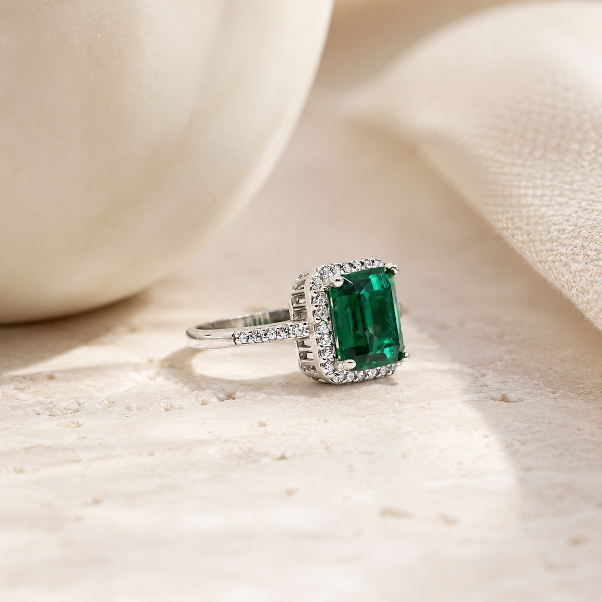 Silver-tone ring with a vivid green emerald-cut center stone.
