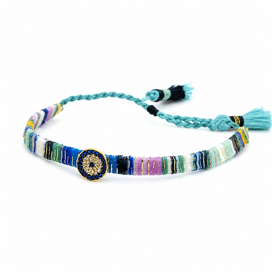 Multicolor woven fabric bracelet with a jeweled evil eye centerpiece and tassel ties.