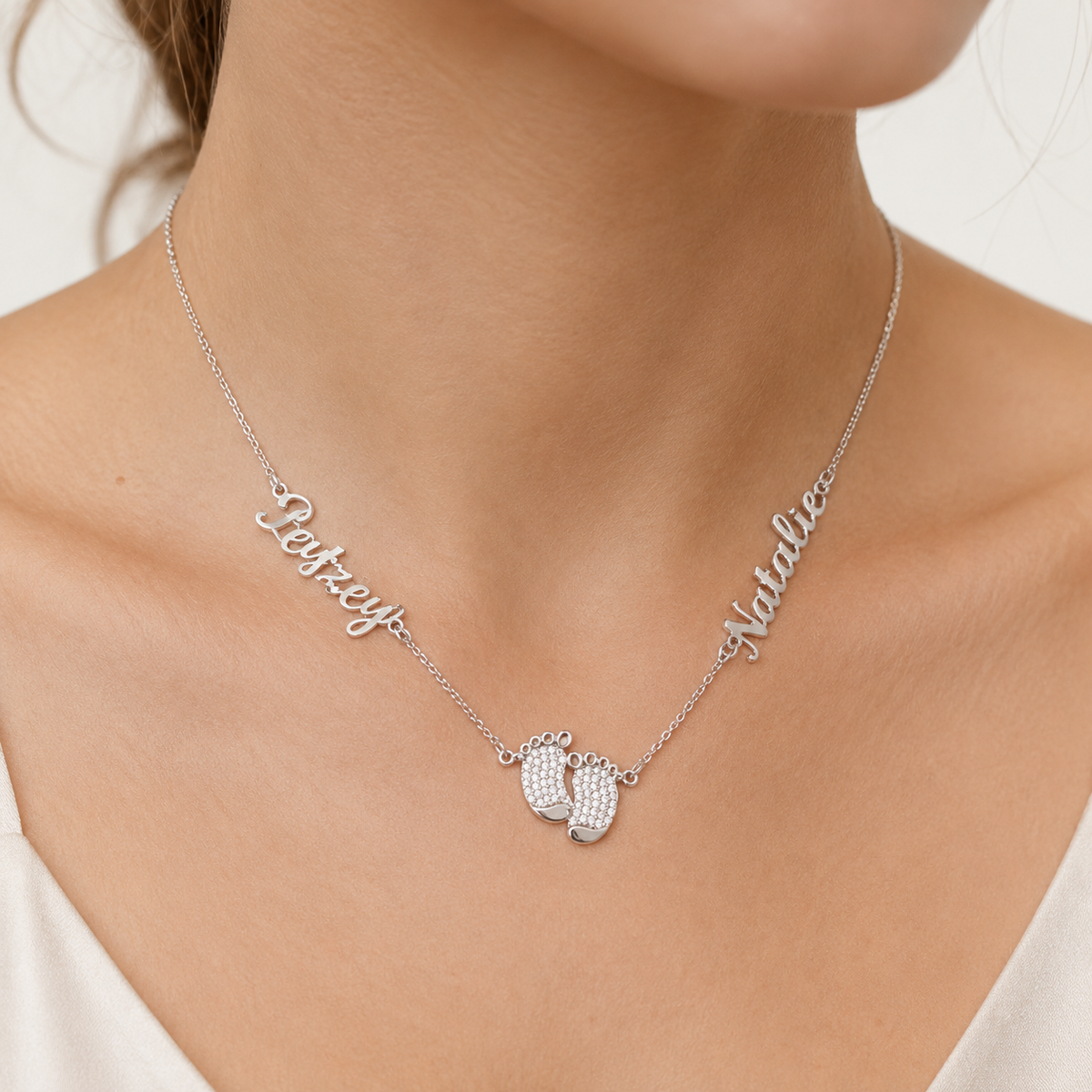 Silver-tone personalized necklace with a baby feet pendant and engraved name details.