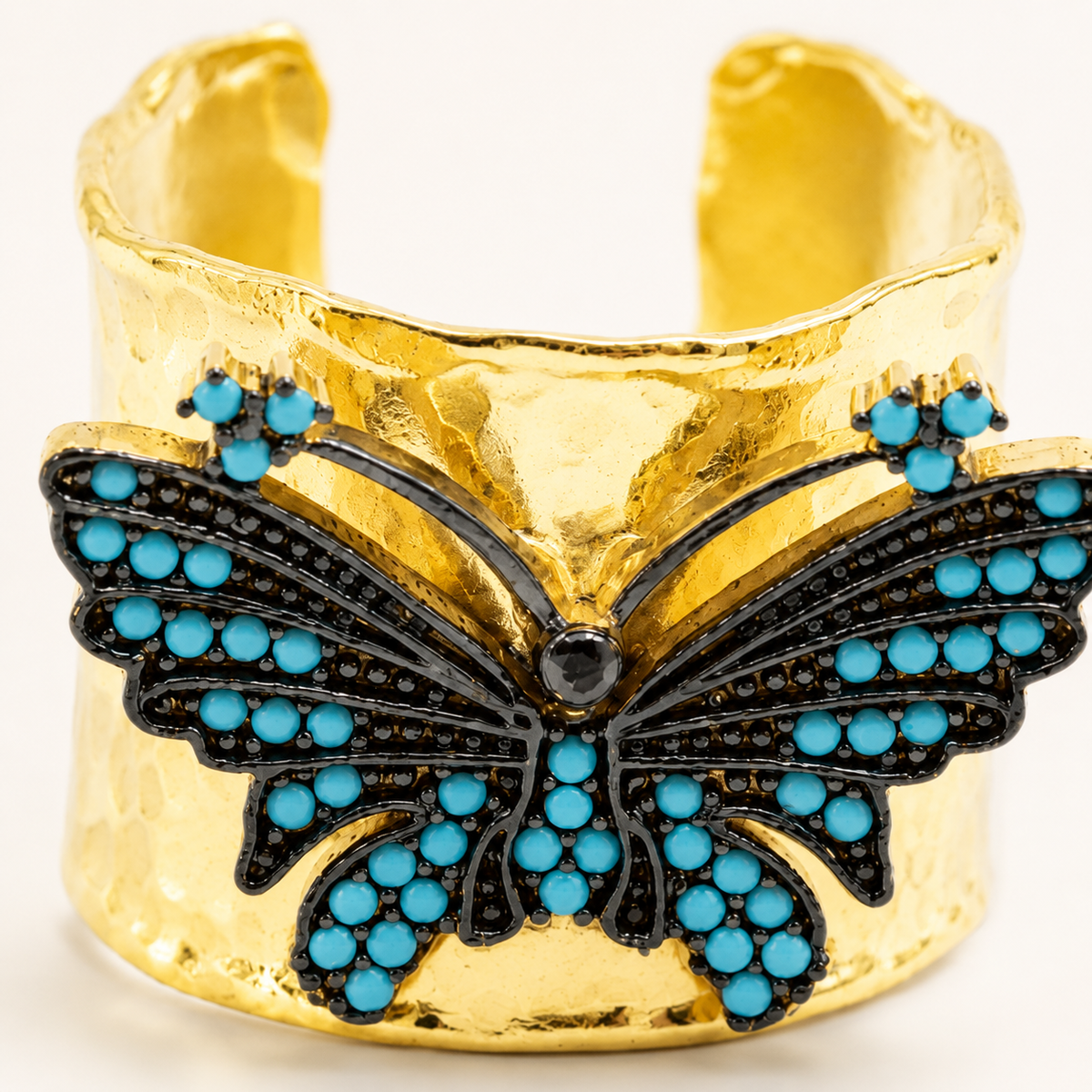 Close view of a gold-plated butterfly cuff ring with turquoise blue accents.