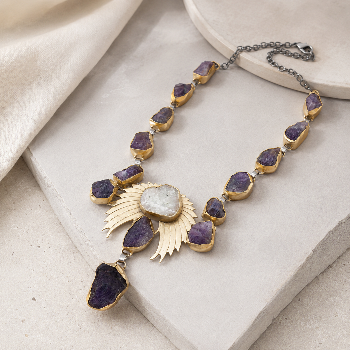 Angled view of the amethyst crystal wing statement necklace with textured purple stones.
