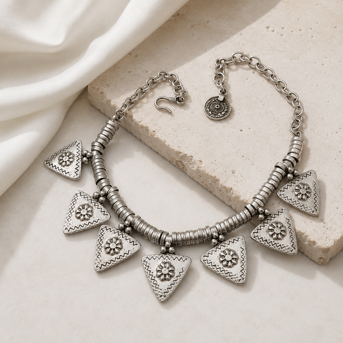 Silver-tone charm necklace with multiple triangle pendants arranged on a white background.