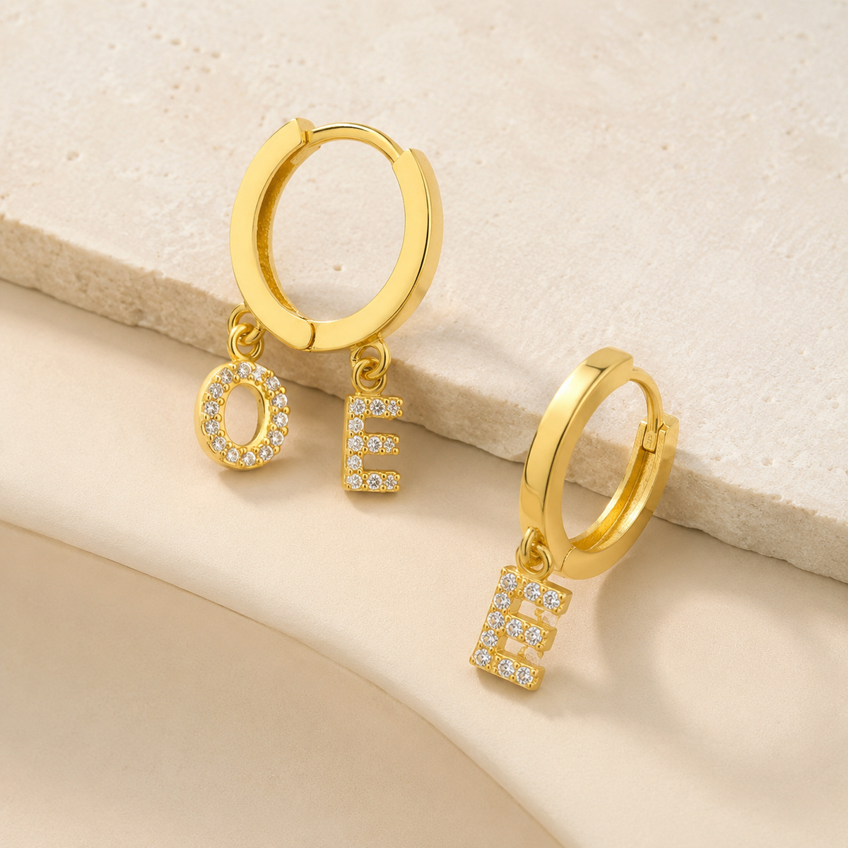 Side view of a gold-tone hoop earring with CZ initial charms.