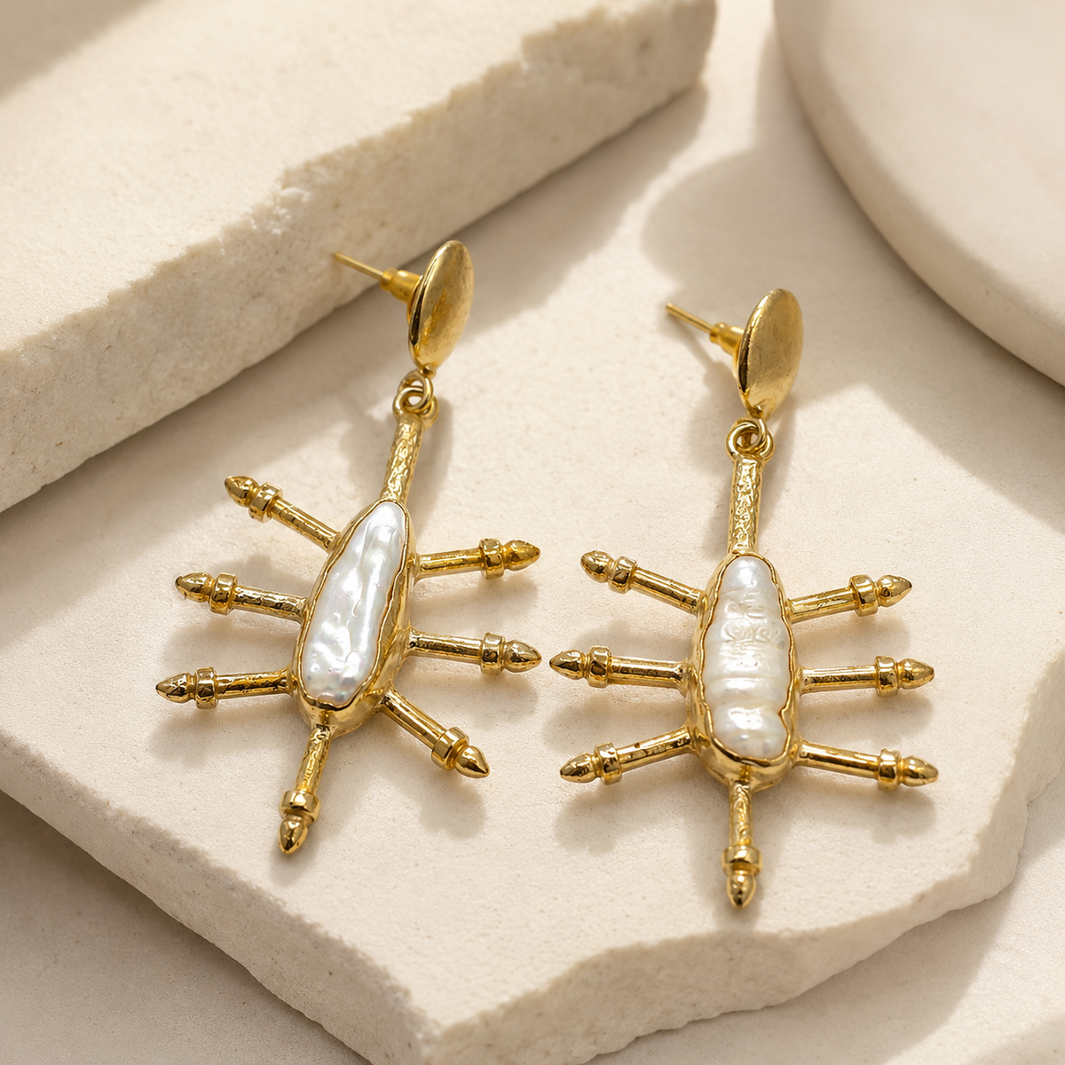 Angled view of gold-plated hook earrings with a cushion-shaped blue sapphire look and drop design.