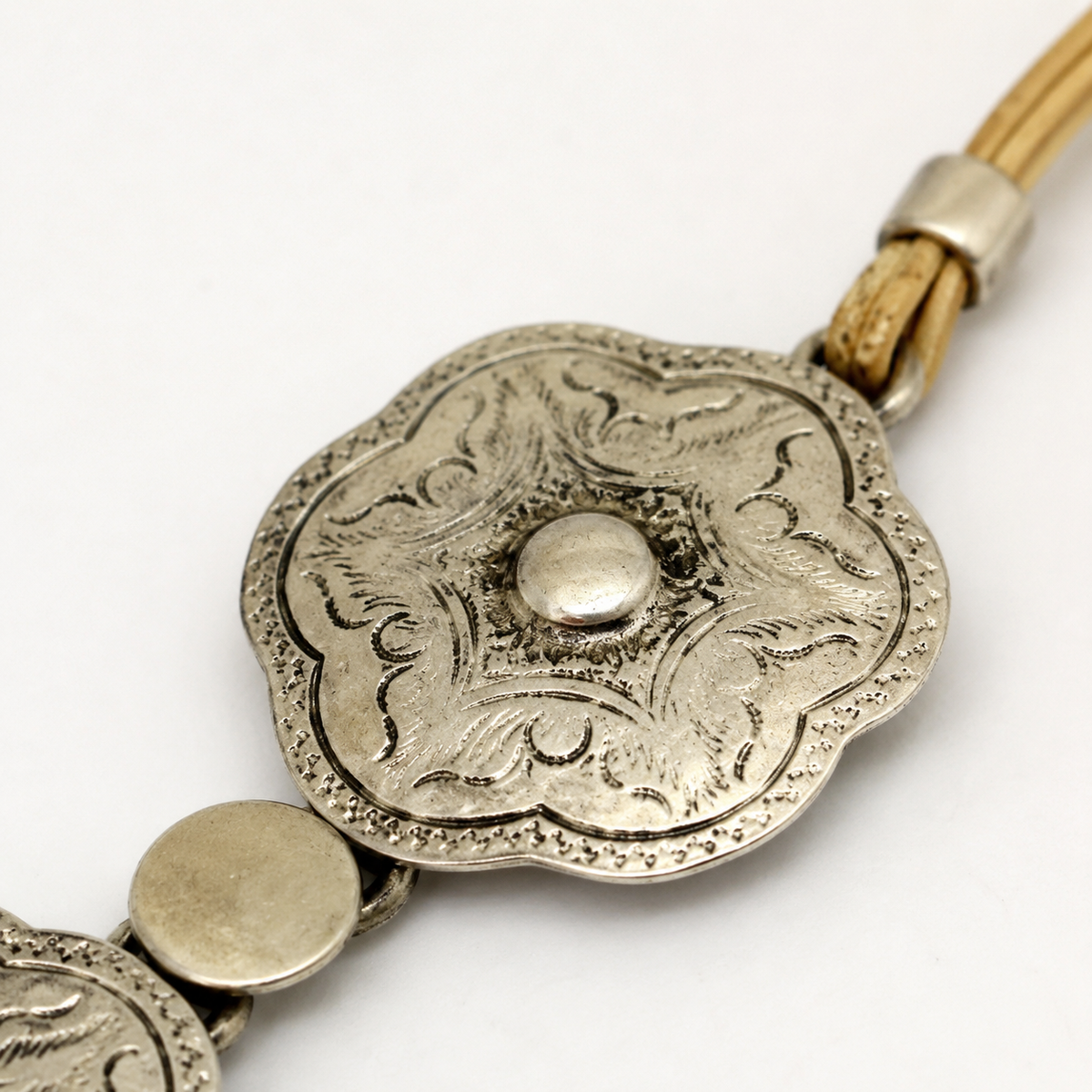 Close view of the engraved floral plate pendant with a polished center detail.