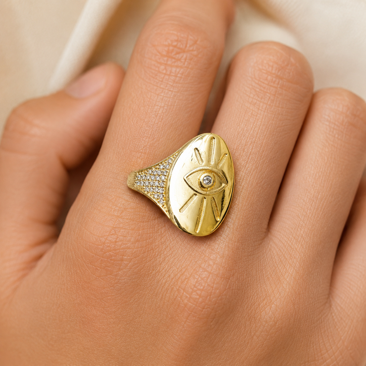 Gold-tone evil eye signet ring shown from the front with a sculptural shape.