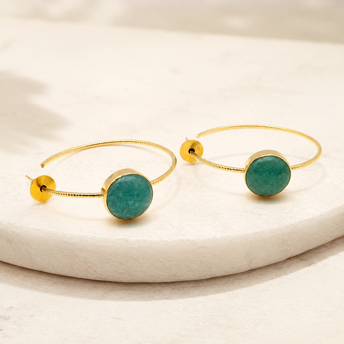 Angled view of gold-plated hoop earrings with green aventurine disc accents.