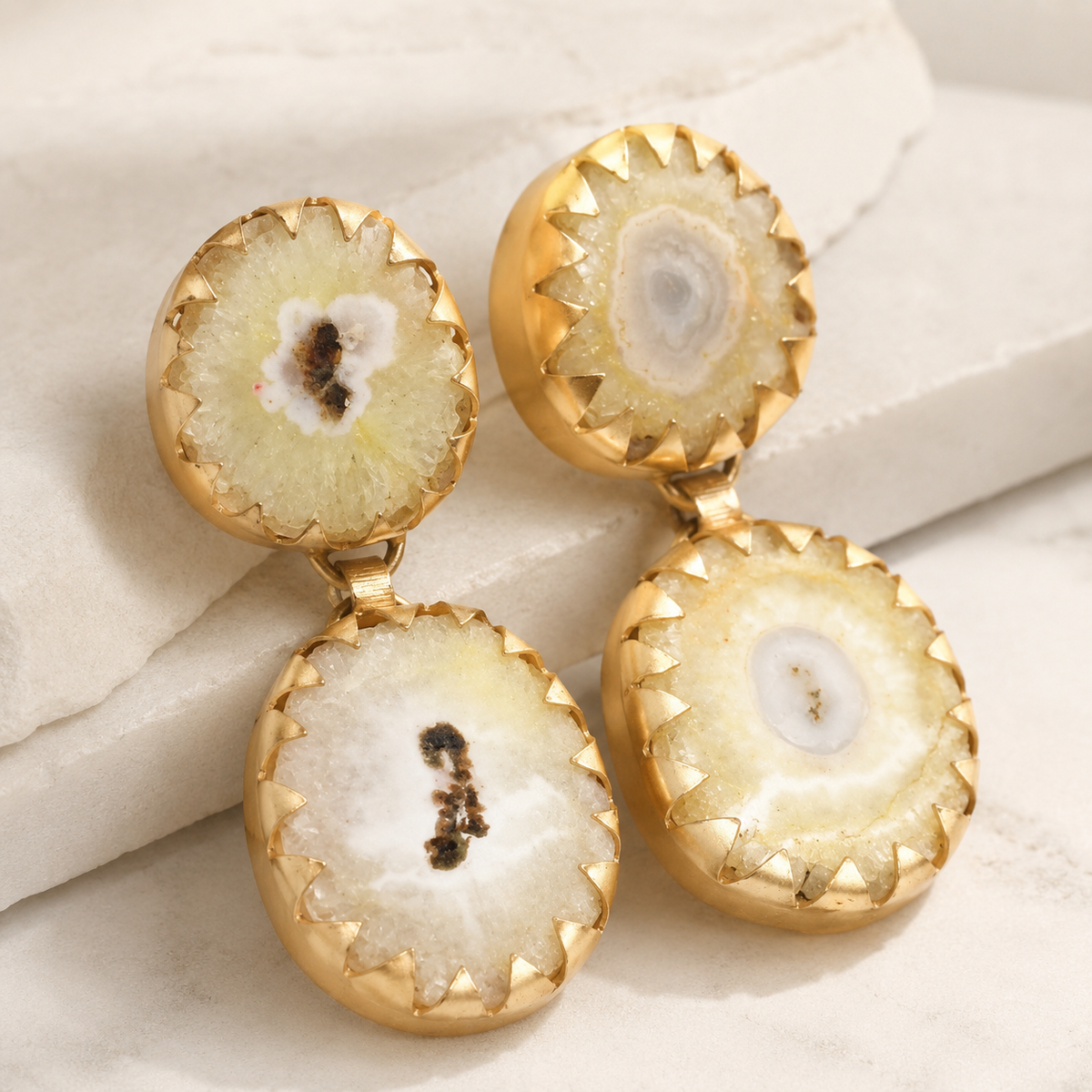 Angle view of yellow agate drop earrings with a gold-plated finish and rounded silhouette.