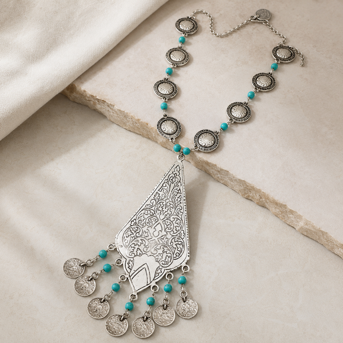 An angled view of the silver-tone necklace with turquoise beads and a teardrop pendant.