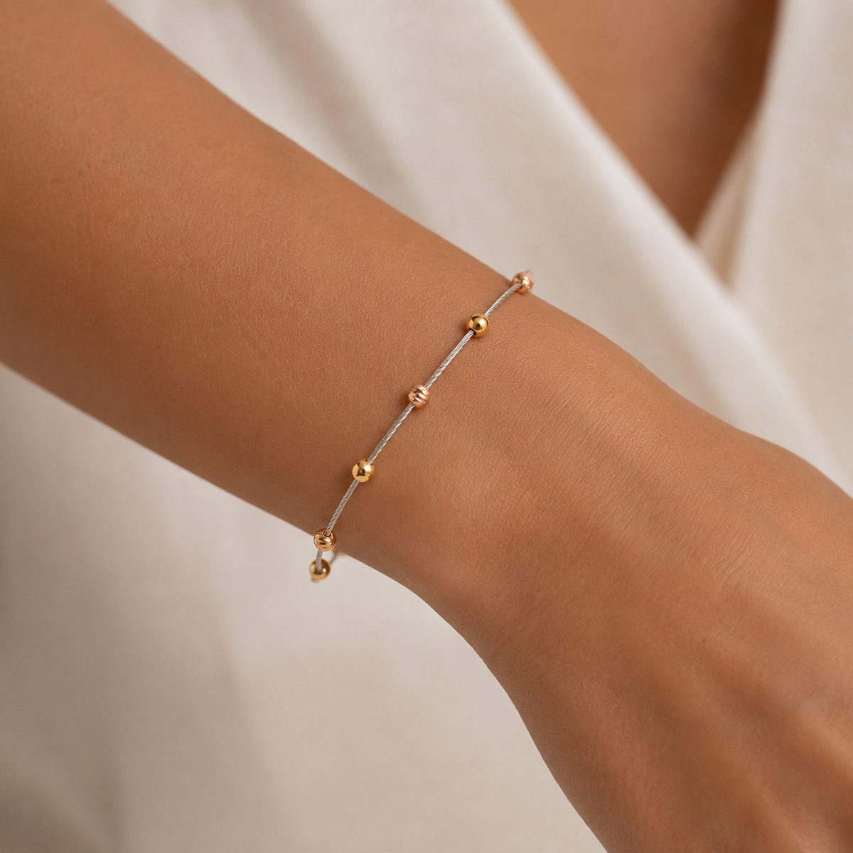 Dorika bracelet shown from above with polished gold-tone and rose-tone bead accents.