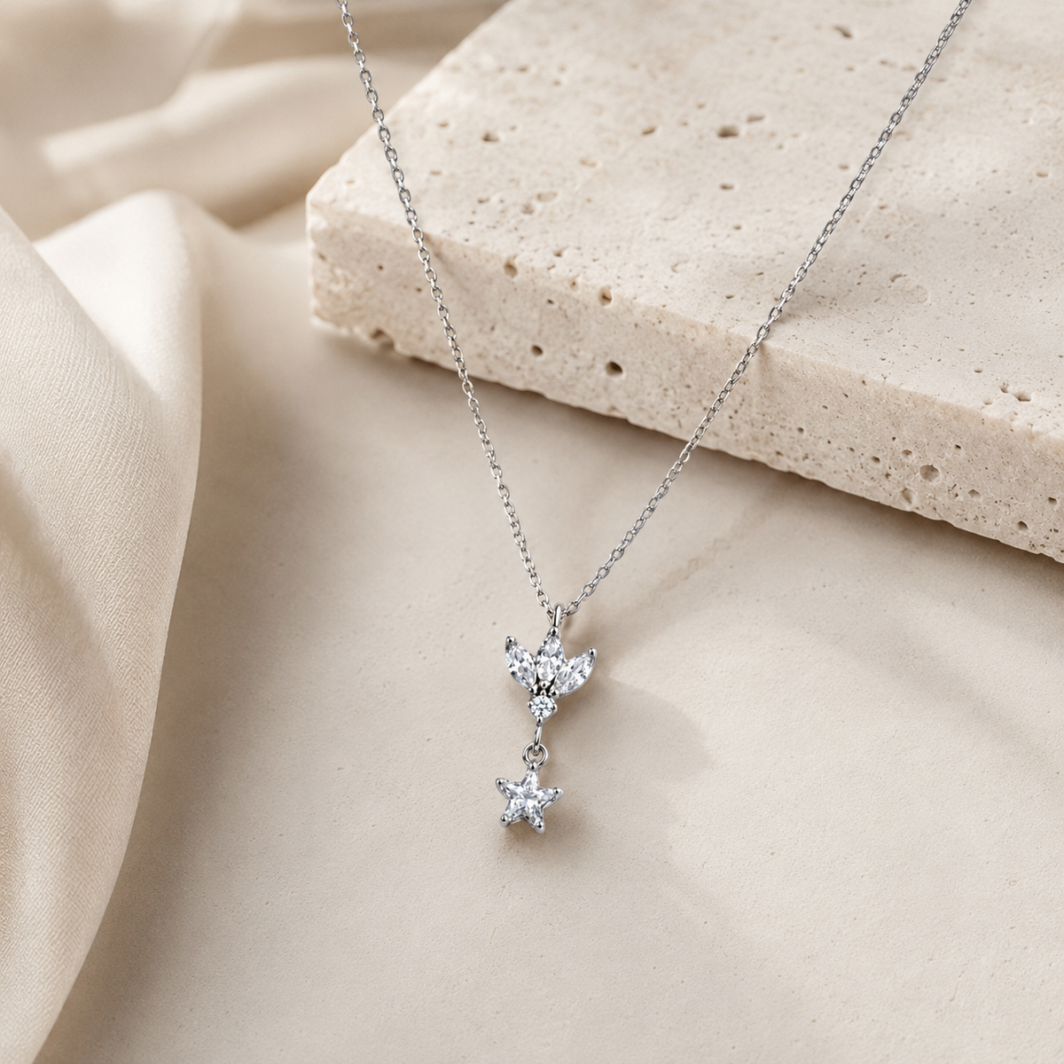 A silver-tone pendant necklace with a lotus-inspired charm and clear star drop.