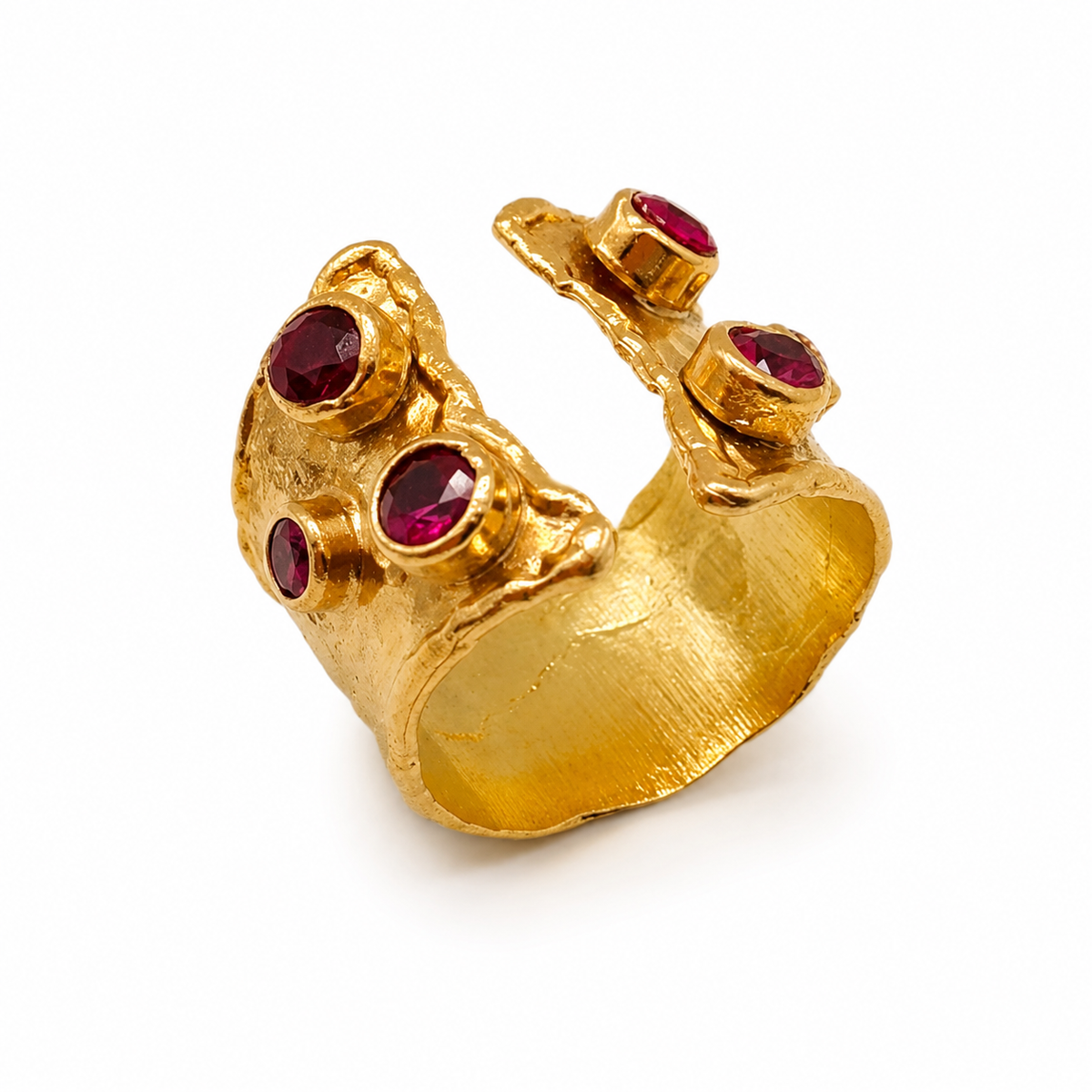 Gold-plated open cuff ring with ruby pink stones and a textured sculptural shape.