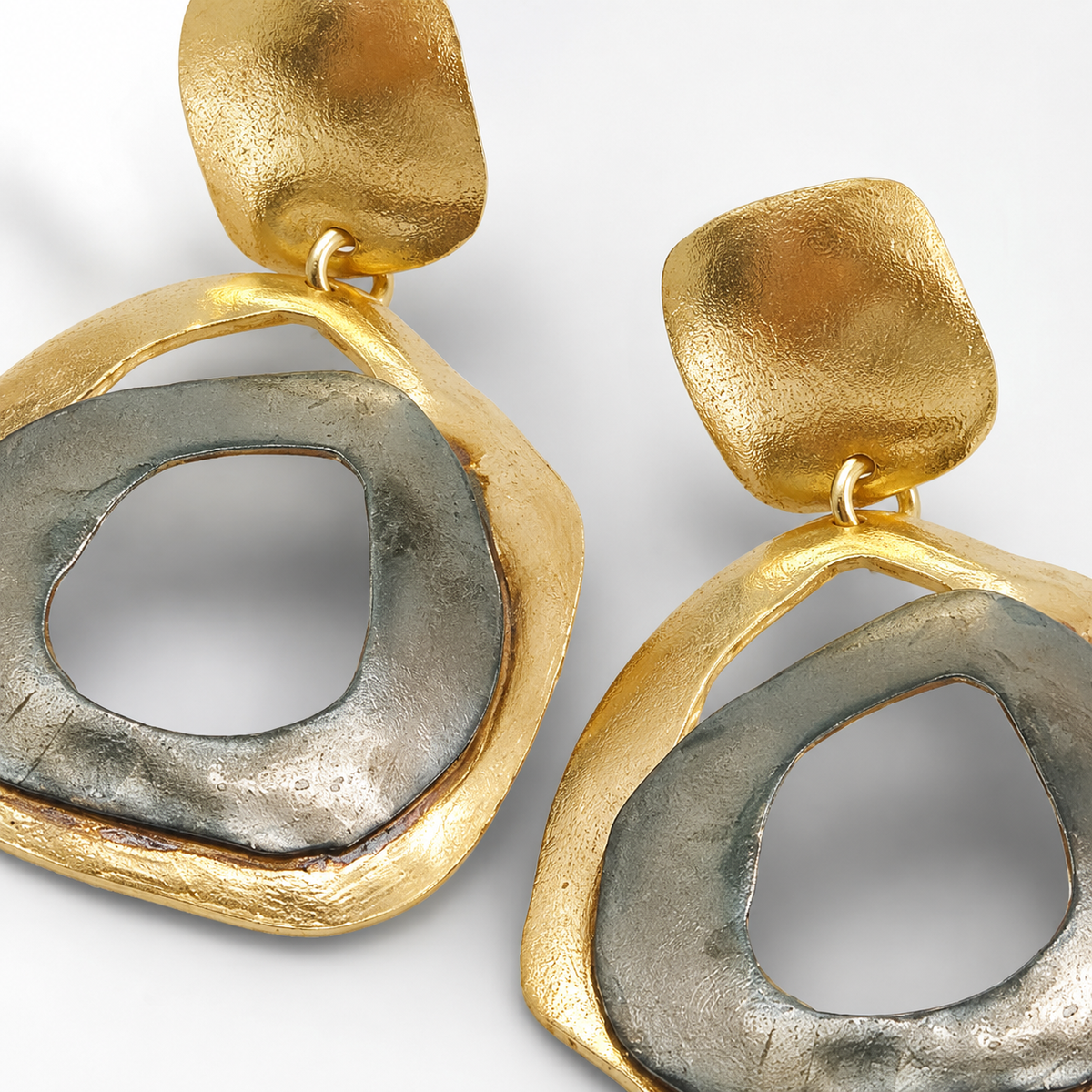 Close view of abstract circle earrings with a softly textured surface.