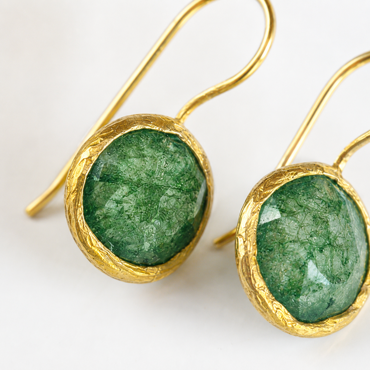 Close view of green CZ-style stones in a gold-plated setting.
