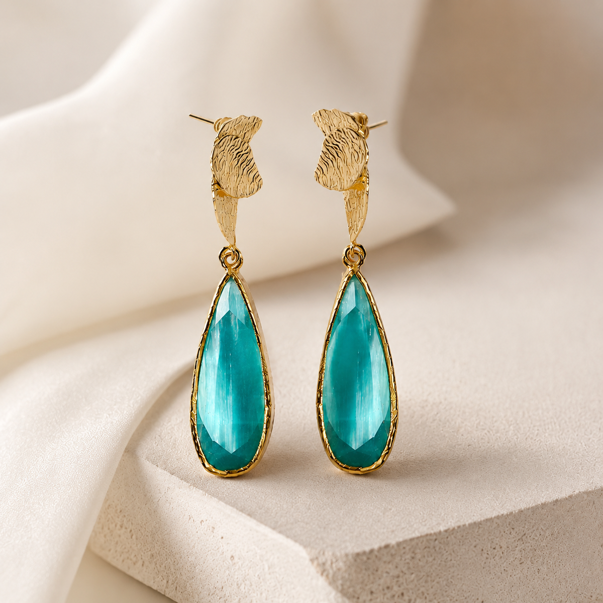 Angle view of turquoise teardrop drop earrings with a gold-plated finish.