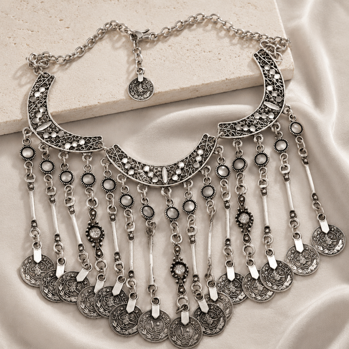 Silver-tone statement necklace with layered crescent and coin fringe design.