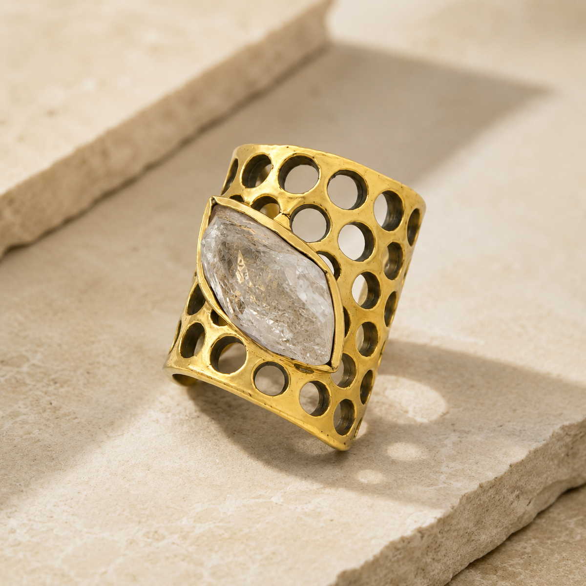 Angled view of a clear quartz honeycomb-style statement ring in gold plating.