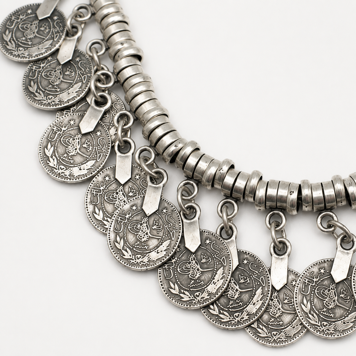 Close view of the silver-tone coin discs and layered collar detail.