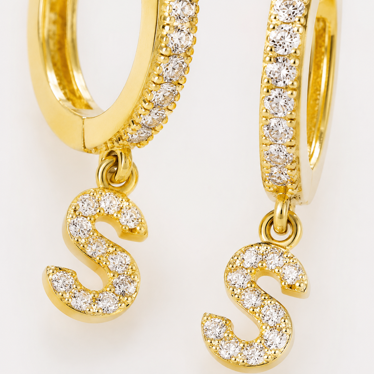 Close view of the gold-tone huggie and clear CZ stone detailing on the initial earrings.