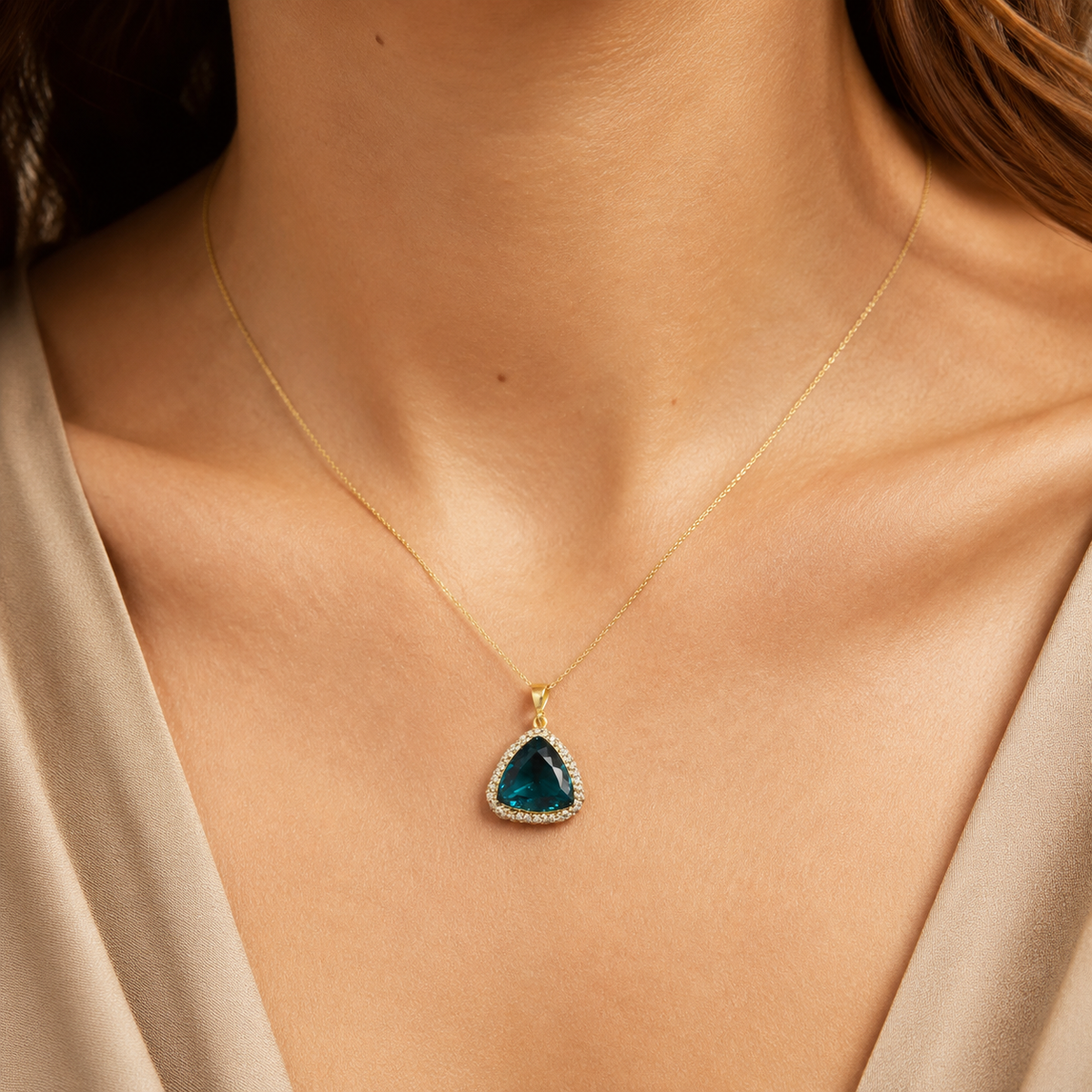 Gold-tone necklace with a faceted green triangle pendant.