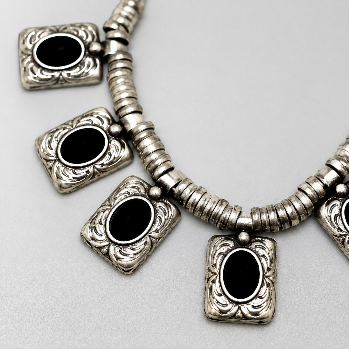 Close view of the black oval charm and ornate silver-tone detailing.