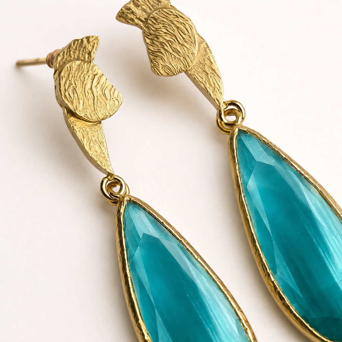 Gold-plated earrings with turquoise drops and a sculpted floral-inspired top.