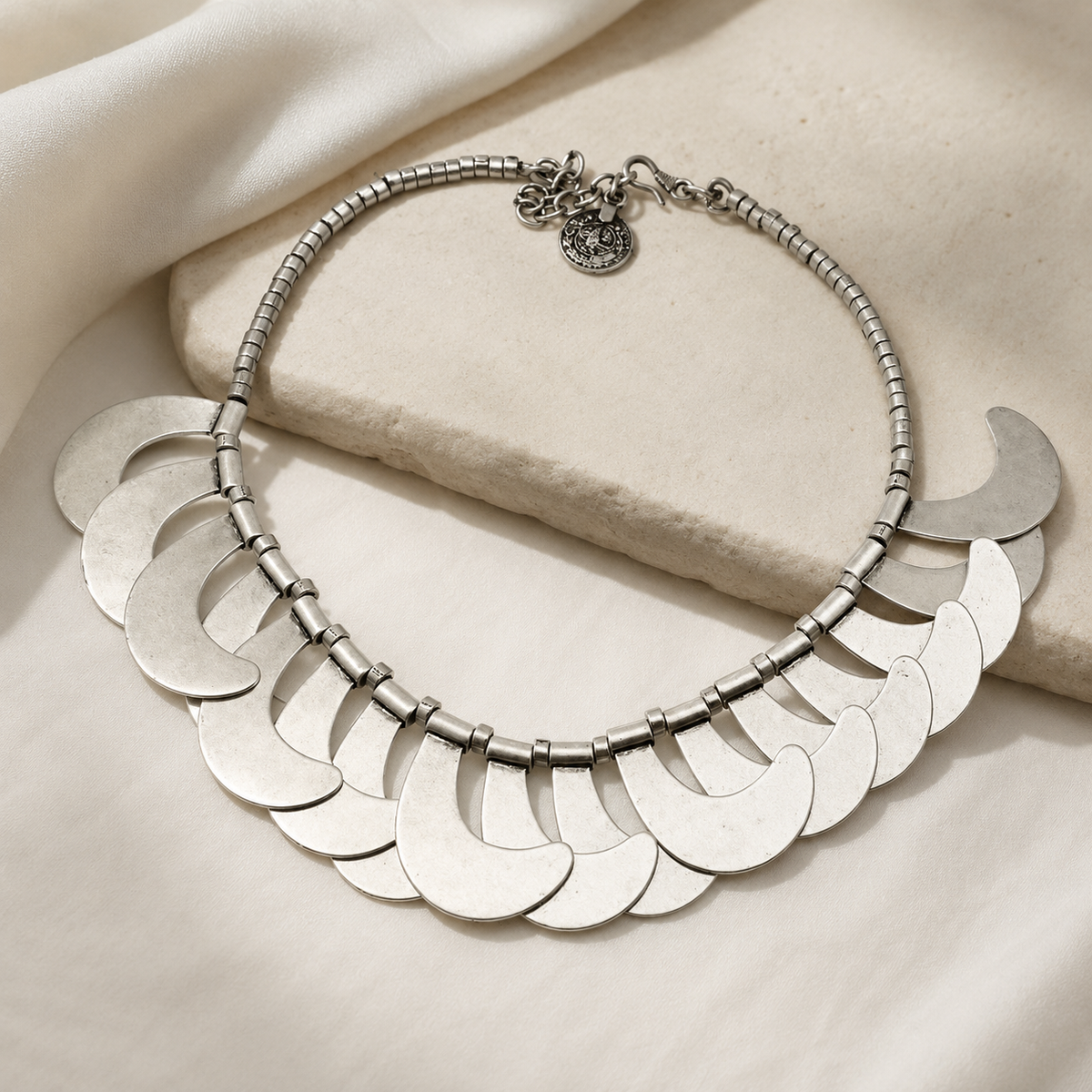 Silver-tone collar necklace with a sculptural crescent shape.