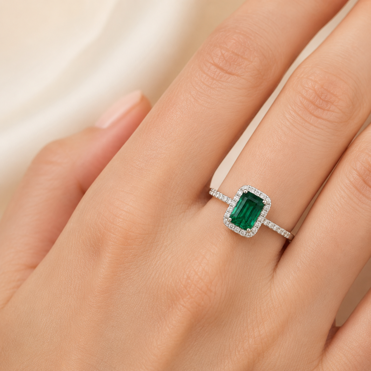 Emerald cut ring shown at an angle with a green stone and sparkling details.