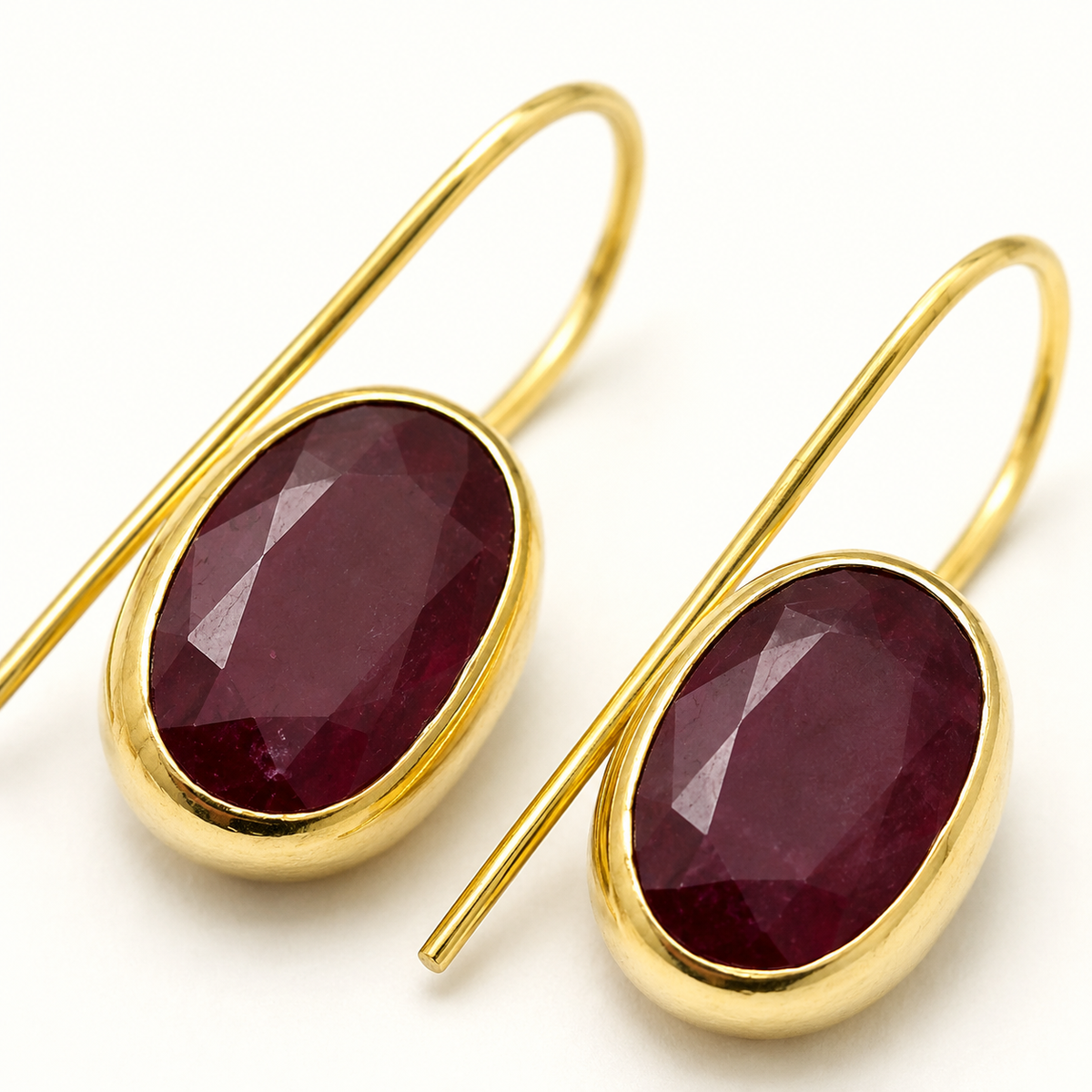 Close-up of gold-plated drop earrings with faceted oval stones.