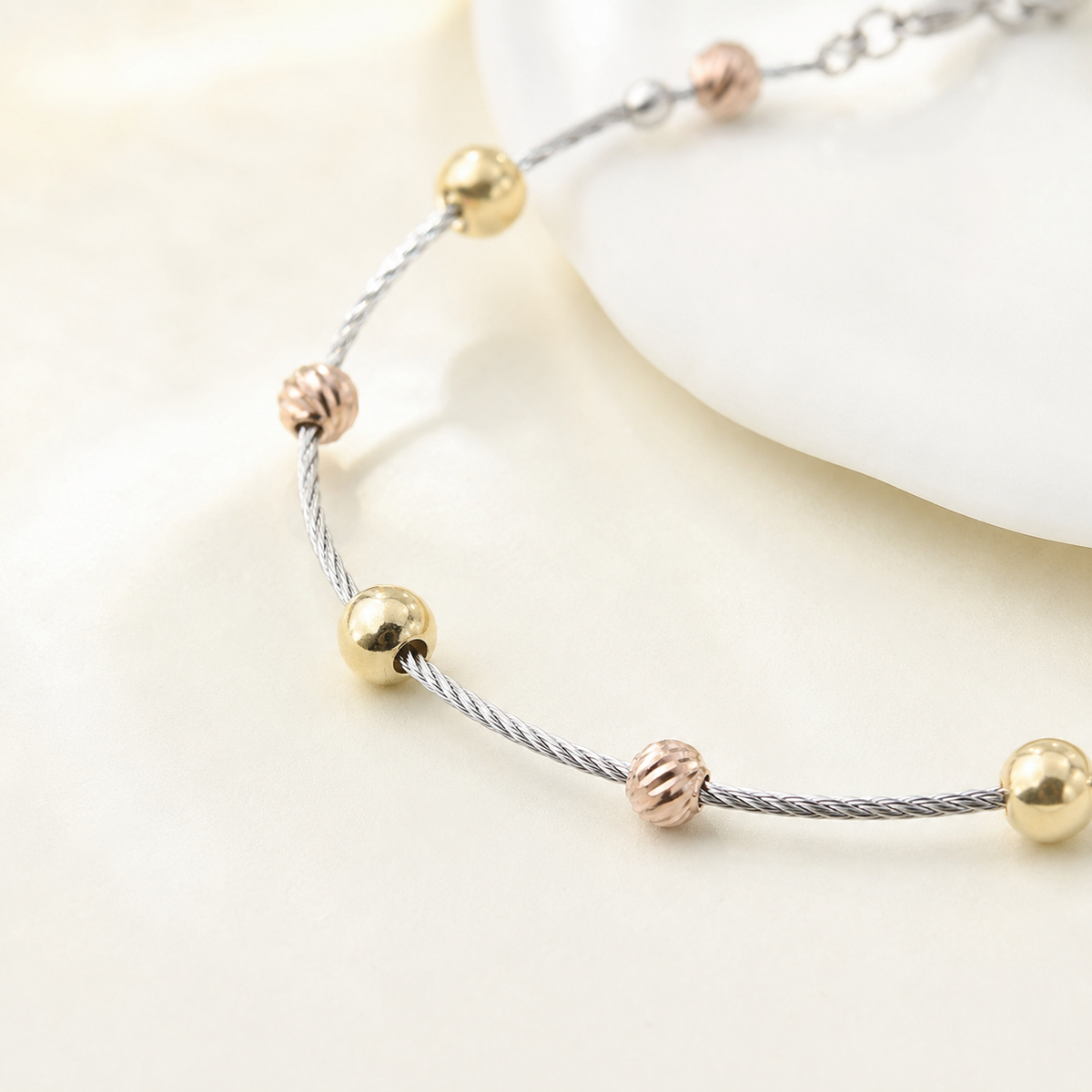 Close view of the bracelet’s textured metallic beads and cable chain.