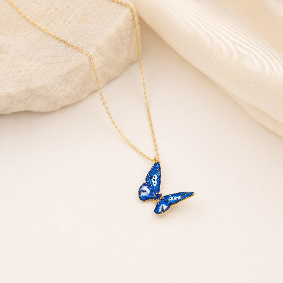 Gold-tone butterfly necklace with vivid blue pendant styling.