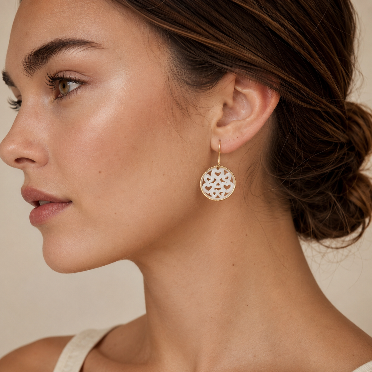 Gold-plated drop earrings with mother of pearl heart cutouts.