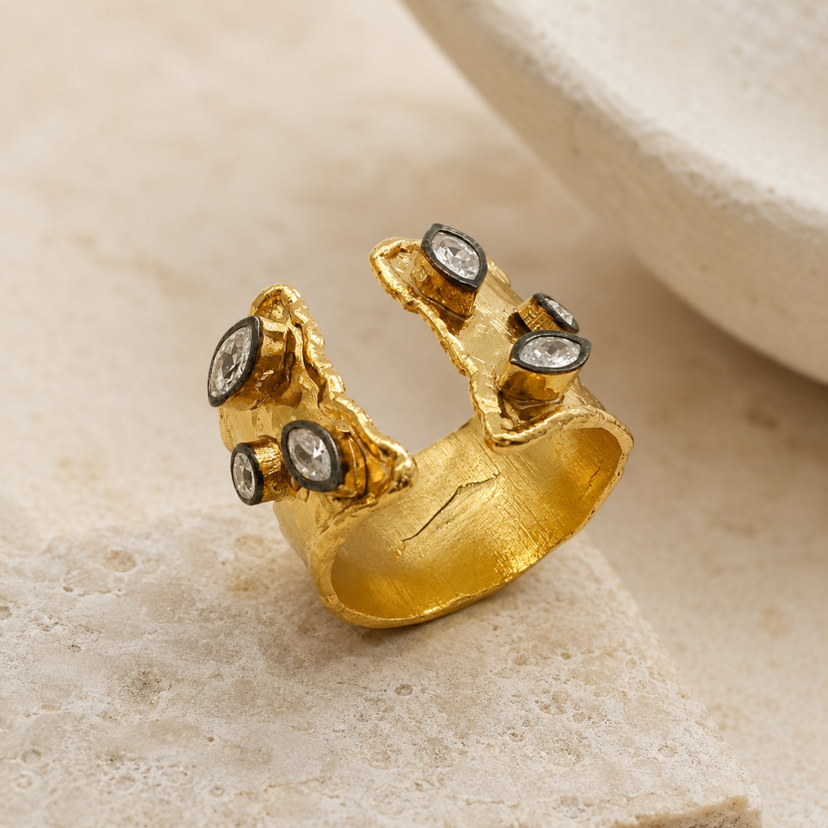 Side angle of a gold-plated open cuff ring with clear quartz accents and textured finish.