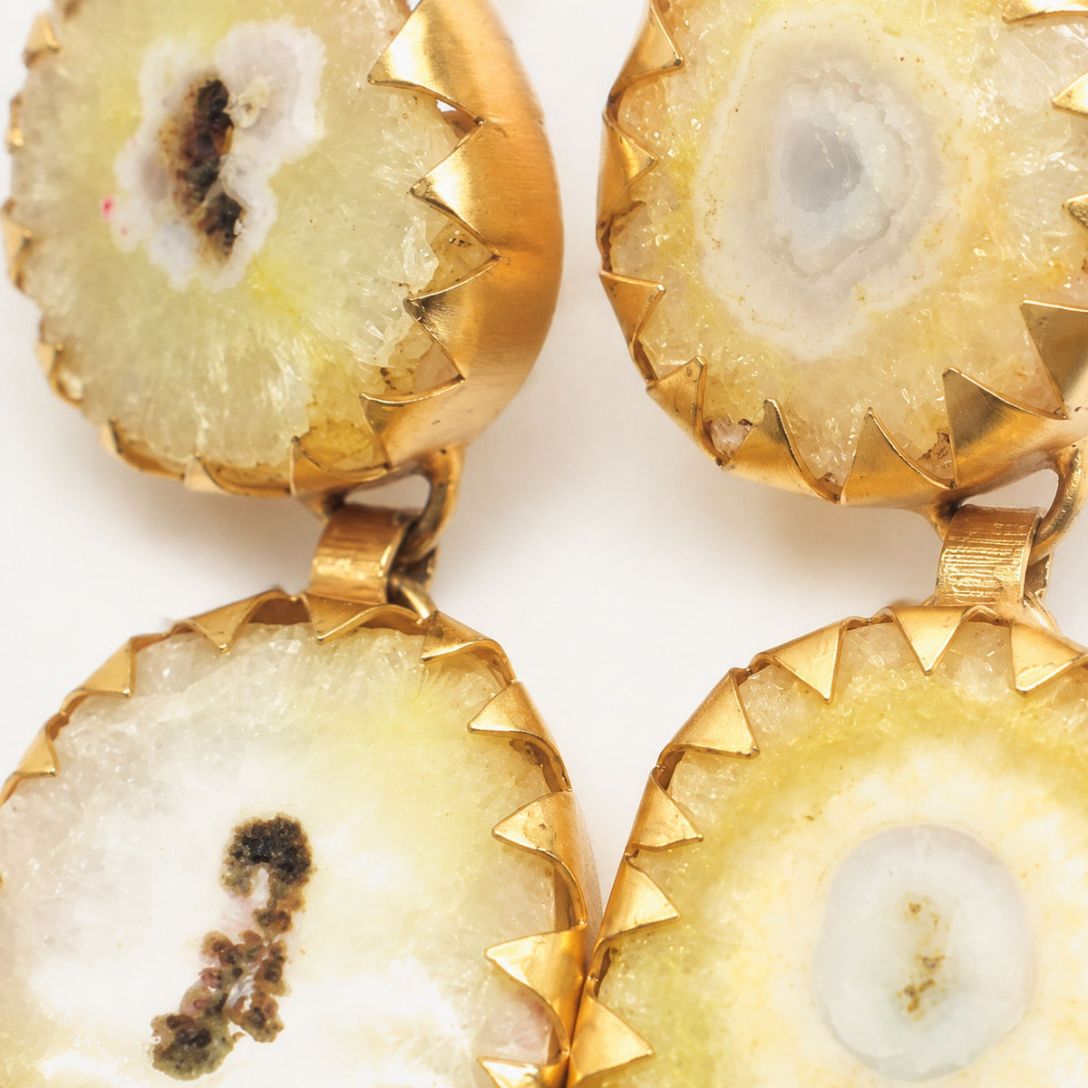 Close view of yellow agate earrings with textured stone detail and gold-plated edges.