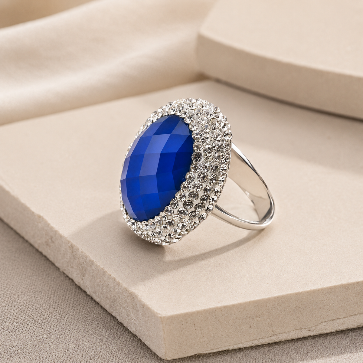 Side angle of a blue stone ring with a faceted center and clear accent frame.