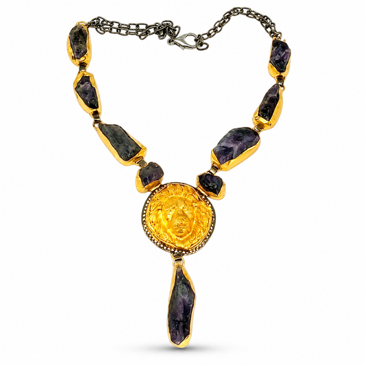 Purple raw stone statement necklace with a gold-tone sunburst pendant.