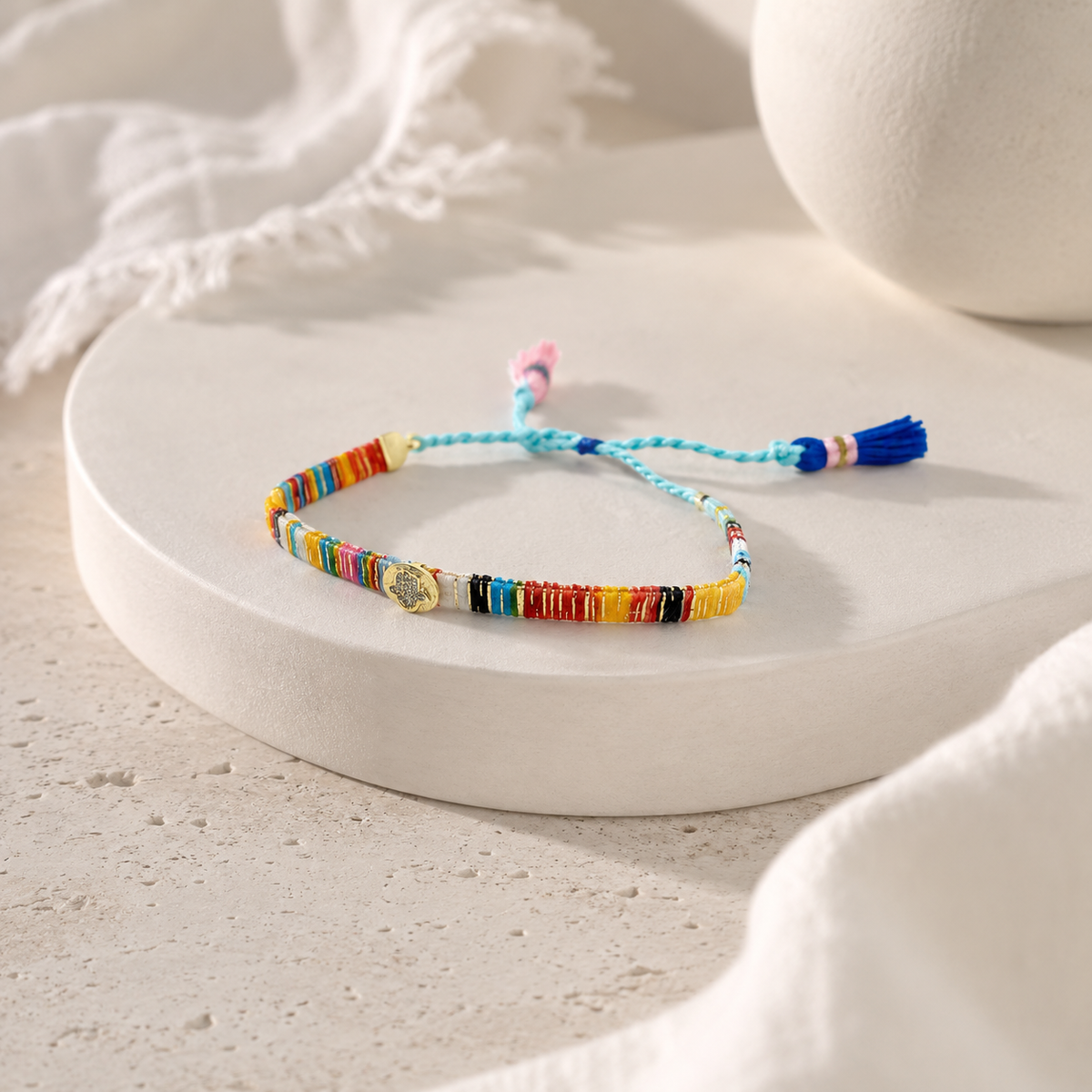 Angled view of a multicolor thread bracelet with braided cord and tassel ends.