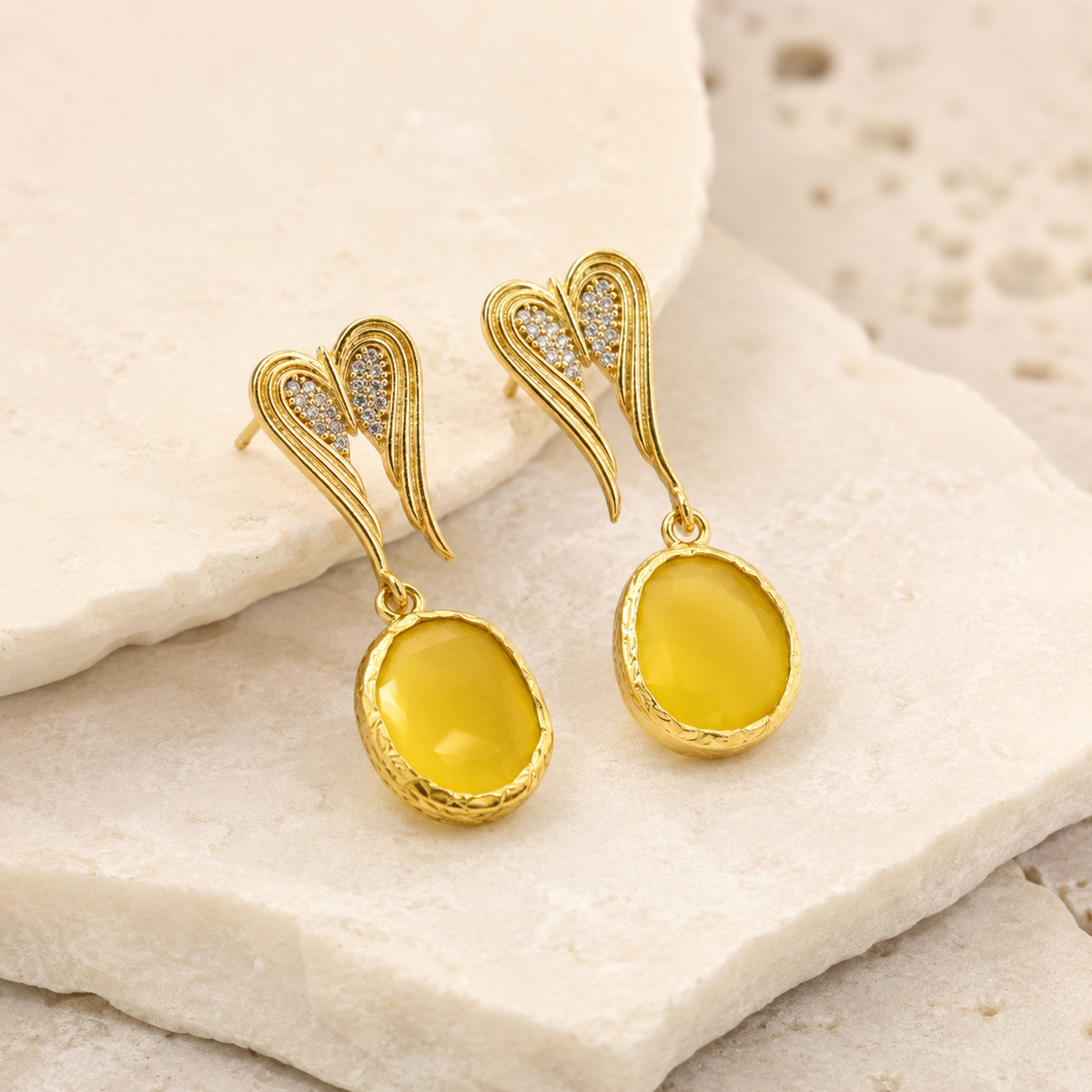 Angle view of gold-tone heart-shaped dangle earrings with crystal detail.