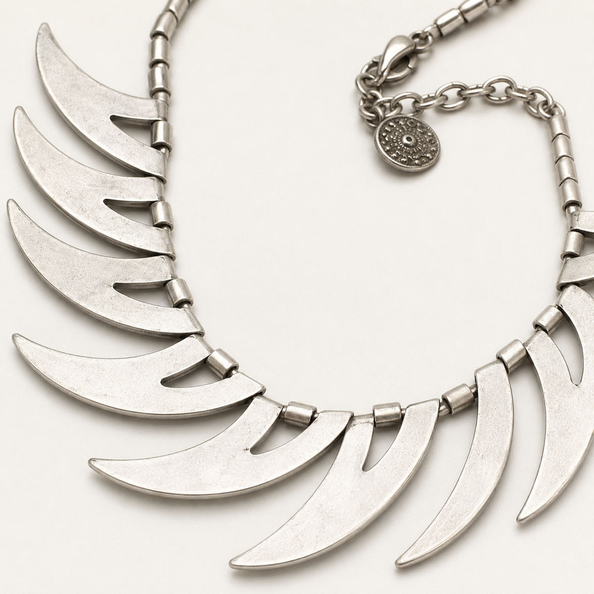Close view of the silver-tone crescent spike necklace detail.