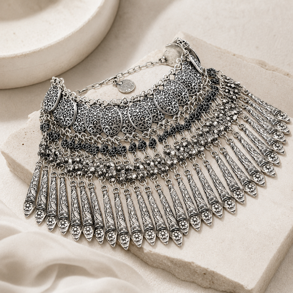 Angled view of the silver-tone coin fringe statement necklace.