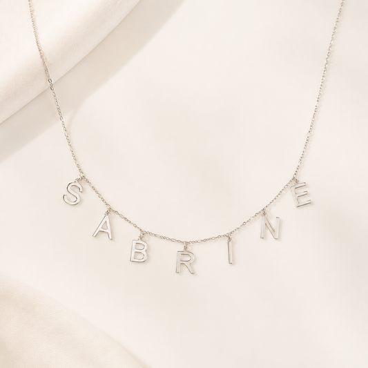 Silver-tone personalized letter name necklace with spaced letter charms on a delicate chain.
