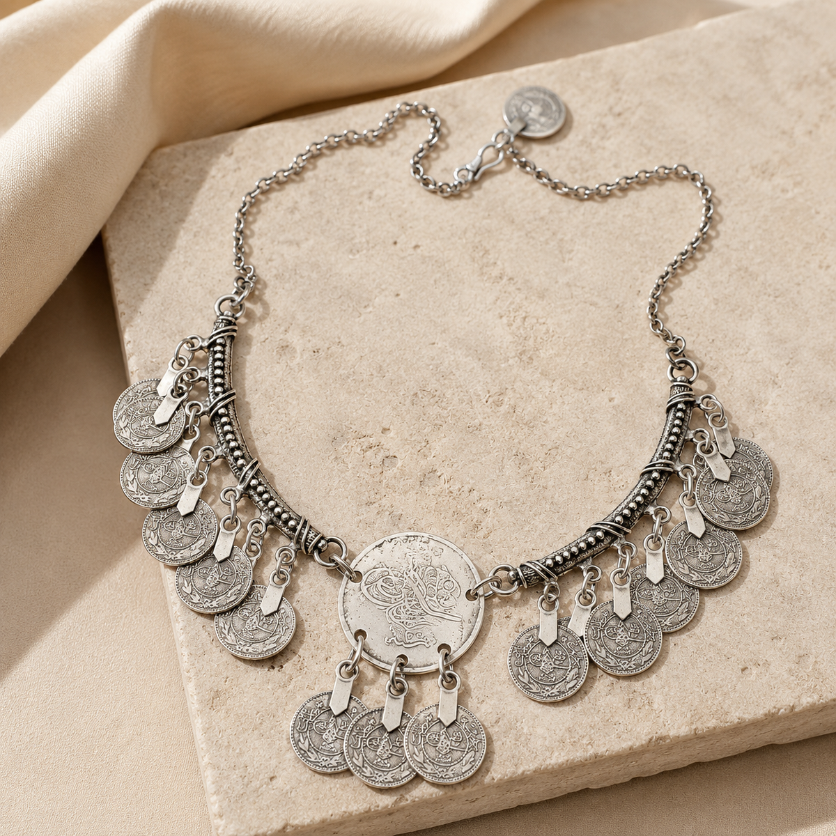Silver-tone statement necklace with textured crescent and fringe coins.