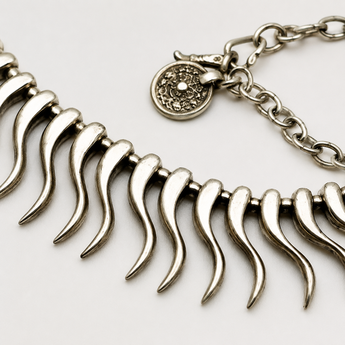 Close view of the necklace's curved spike links and polished silver-tone finish.