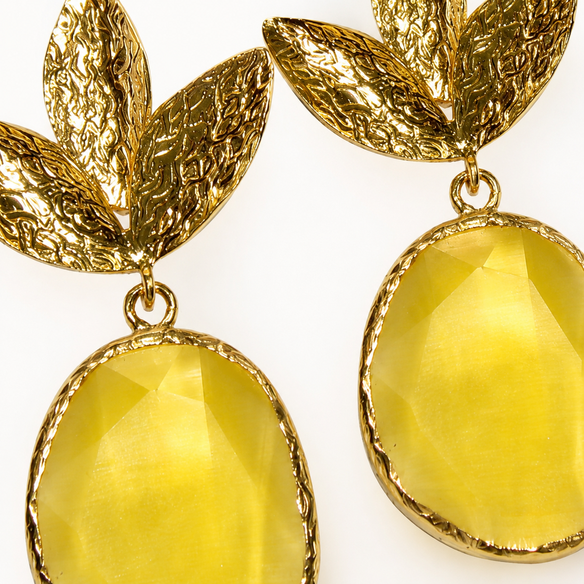 Close view of textured leaf earrings with a faceted mustard yellow drop.