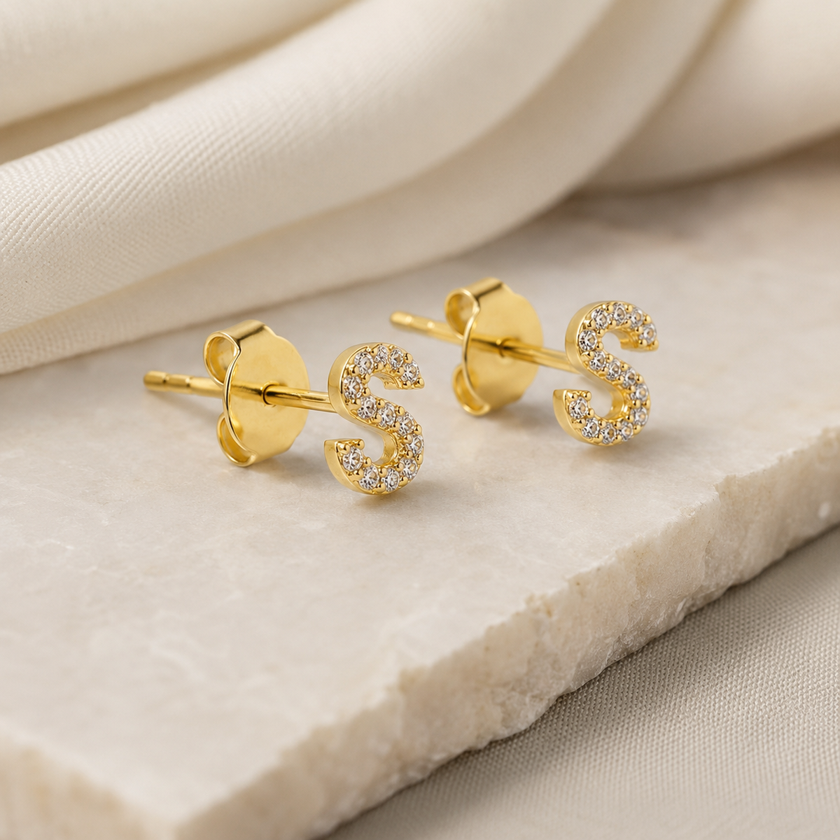 Angled view of a gold-tone CZ initial stud earring.