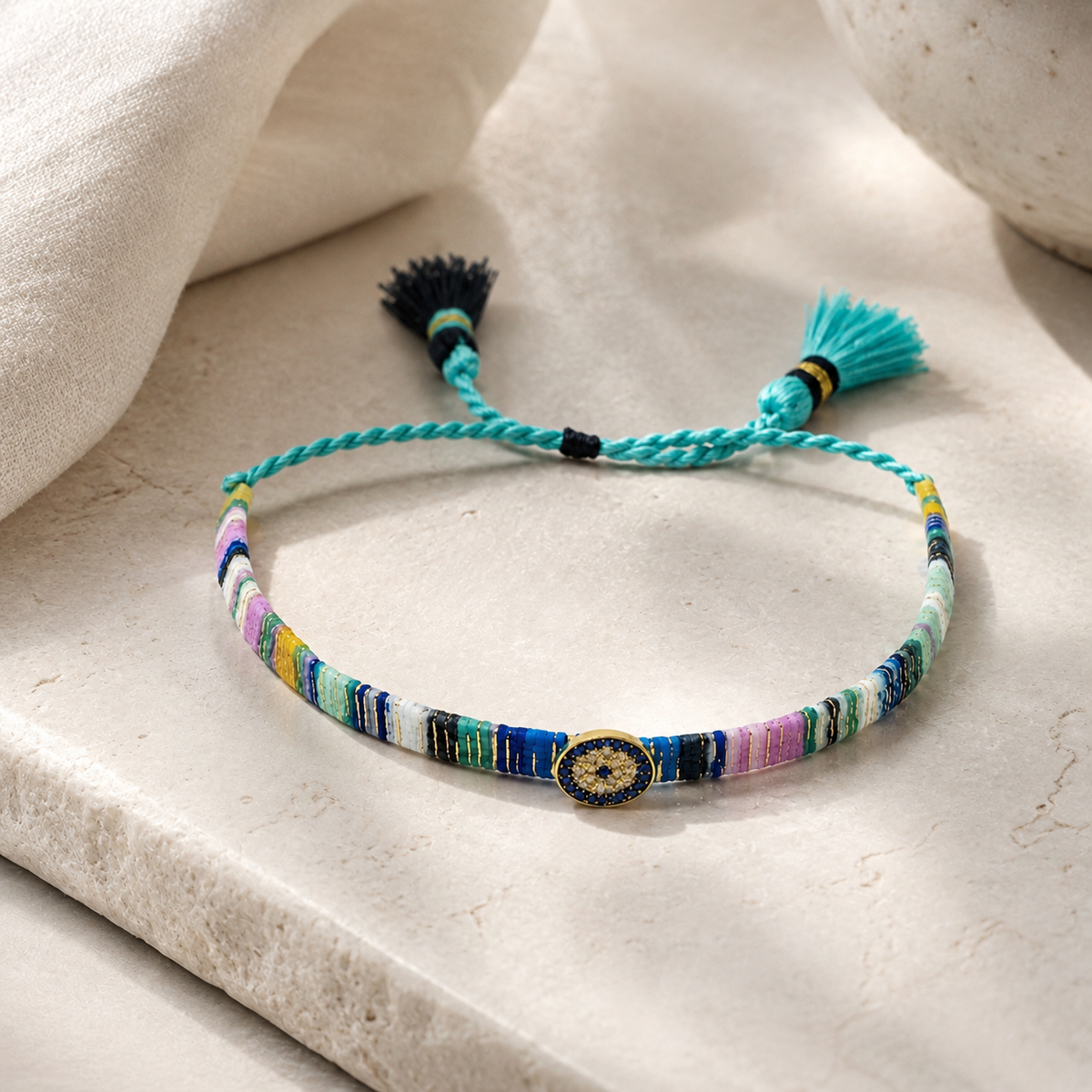 Colorful thread bracelet with tassel ties and a small evil eye detail.