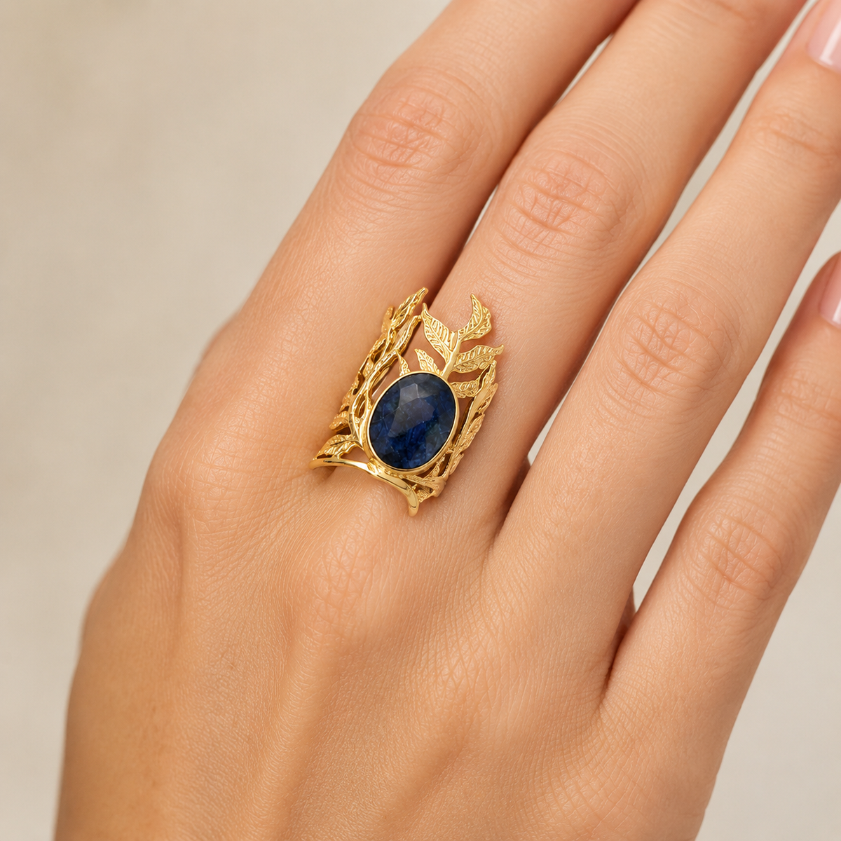 Angled view of a gold leaf filigree ring with a navy blue oval center stone.